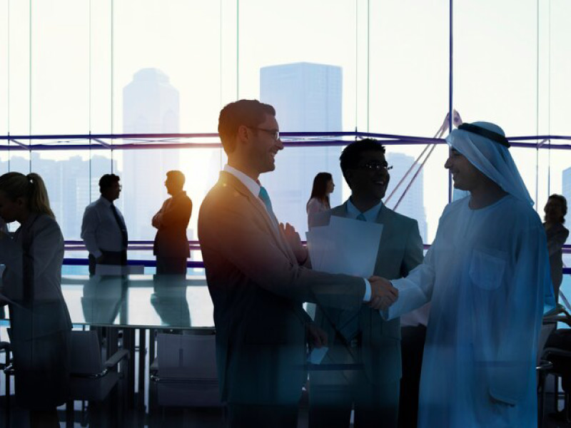 Two business professionals shaking hands in an office setting.